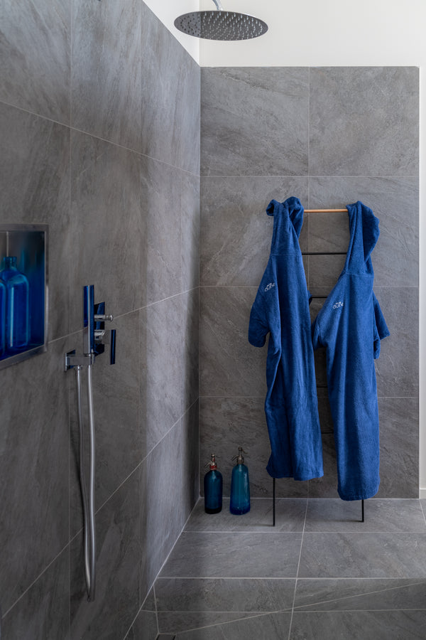 2 ponchos outremer Bio sont suspendus dans une grande douche italienne avec accessoires de déco outremer