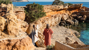 Trois femmes descendant des escaliers vers la plage en ponchos graphite, sable et terracotta - Atelier Dune