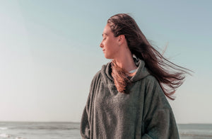 Fille fermant les yeux sur la plage en poncho en coton bio sauge - Atelier Dune