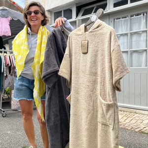 femme souriante au marché tenant un poncho de bain sable - Atelier Dune