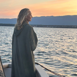 femme sur un bateau regardant le coucher du soleil en poncho de bain sauge - Atelier Dune