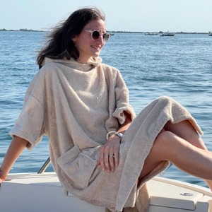 Jeune femme souriante sur un bateau en poncho de bain sable - Atelier Dune