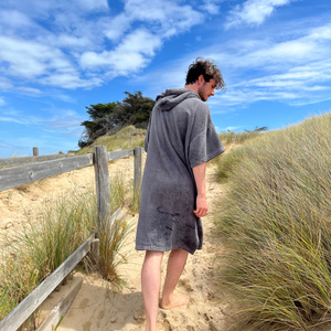 jeune homme marchant sur une dune en poncho de bain graphite - Atelier Dune