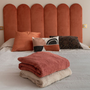 deux ponchos en coton bio terracotta et sable pliés sur un lit - Atelier Dune