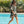Poncho bio kaki sauge porté par une jeune femme au bord d'une piscine - Atelier Dune