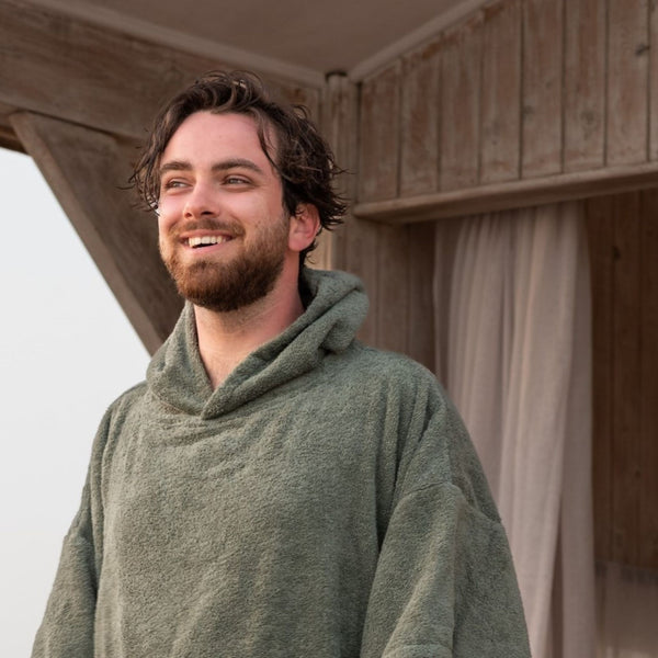 jeune homme regardant l'horizon en poncho de bain en coton biologique sauge - Atelier Dune