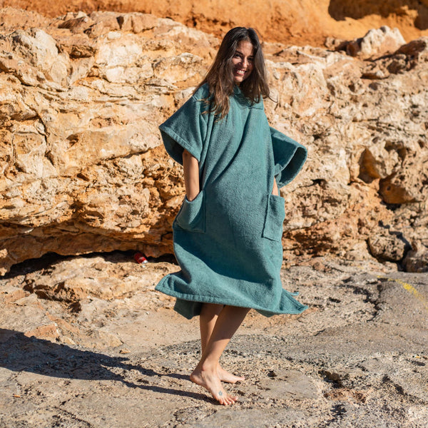 jeune fille souriante qui danse en portant un poncho de bain moelleux en coton biologique céladon - Atelier Dune