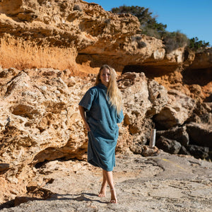 Jeune fille blonde portant le poncho bio lagon dans une calanque à Ibiza - Atelier Dune