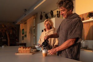 Homme et femme qui boient du café en ponchos en coton bio sable et graphite - Atelier Dune