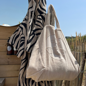 Maxi totebag éponge Bio coloris sable suspendu à côté d'un poncho zèbre salle de bain extérieure  - Atelier Dune