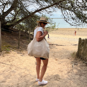 Femme portant a l’epaule le cabas ideal XL en coton bio sable en bord de mer - Atelier Dune