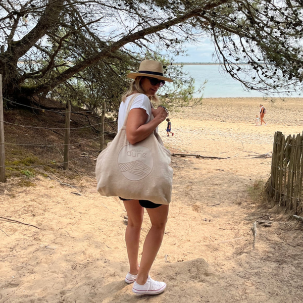 Femme portant a l’epaule le cabas ideal XL en coton bio sable en bord de mer - Atelier Dune