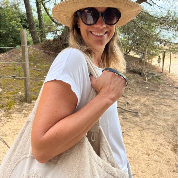 Femme portant a l’epaule le cabas ideal XL en coton bio sable en bord de mer - Atelier Dune