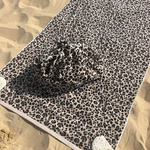 Drap de plage en coton biologique velours leopard pose sur le sable - Atelier Dune