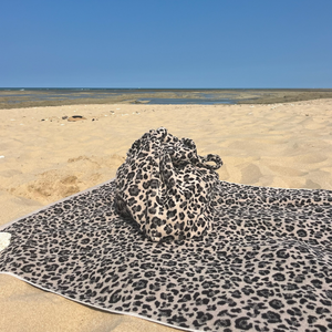 Drap de plage en coton biologique velours leopard pose sur le sable - Atelier Dune