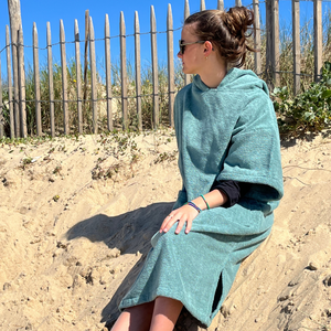 jeune fille assise sur une dune portant un poncho de bain céladon - Atelier Dune