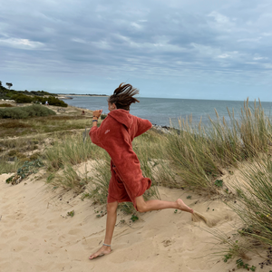 fille qui court en poncho terracotta - Atelier Dune