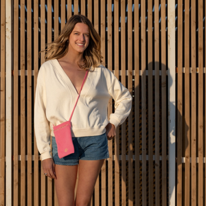 Femme souriante portant la pochette bandouliere en molleton biologique coloris rose fuschia - Atelier Dune