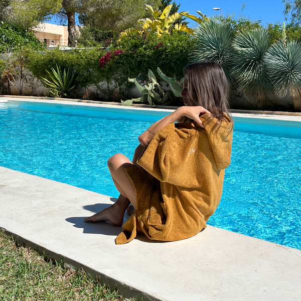 Jeune femme au bord de la piscine en poncho de bain coton bio coloris caramel - Atelier Dune