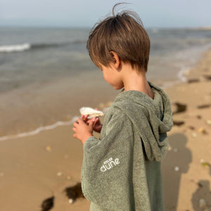Petit garçon a la plage portant un poncho  en coton biologique coloris sauge - Atelier Dune