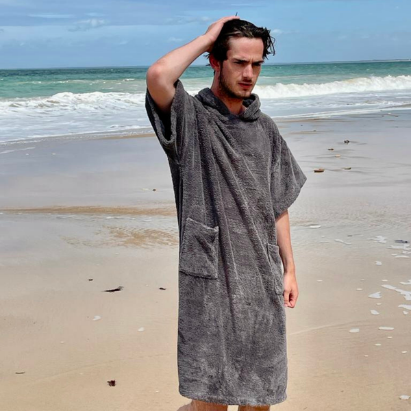 Jeune homme a la plage portant un poncho en coton biologique graphite  - Atelier Dune