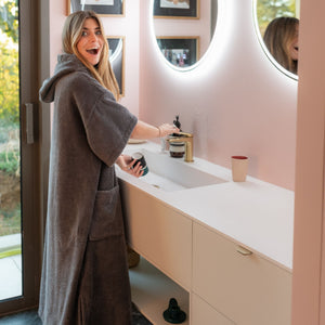 Femme portant un poncho de bain en coton biologique graphite dans sa salle de bain - Atelier Dune