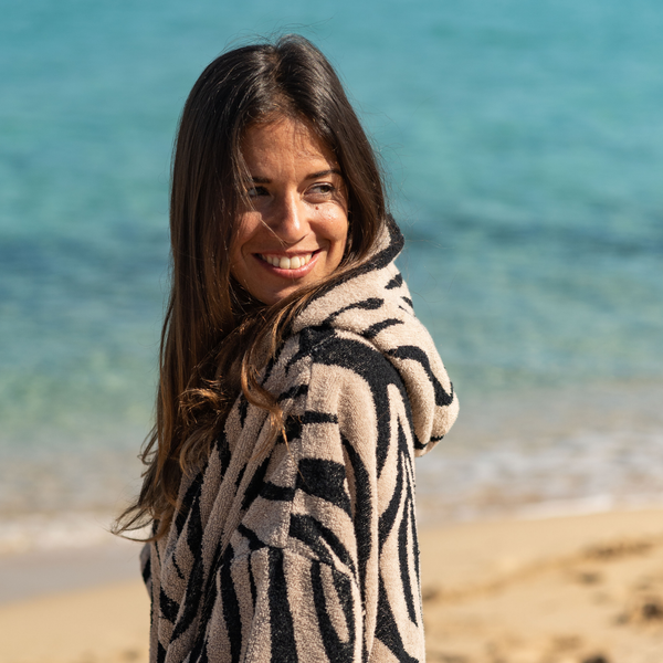 Femme souriante sur la plage en poncho zebre - Atelier Dune