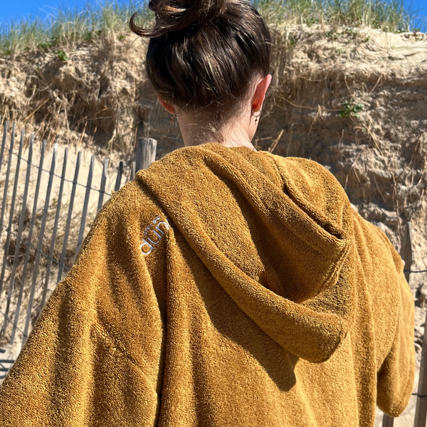 Jeune femme en poncho de plage en coton biologique coloris caramel - Atelier Dune