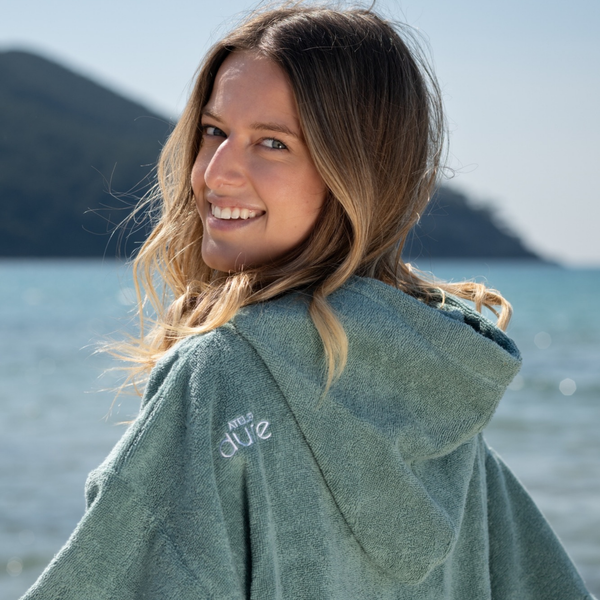 Femme souriante portant un poncho séchant en coton biologique celladon - Atelier Dune