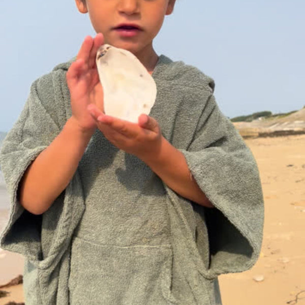 Petit garçon a la plage portant un poncho  en coton biologique coloris sauge - Atelier Dune