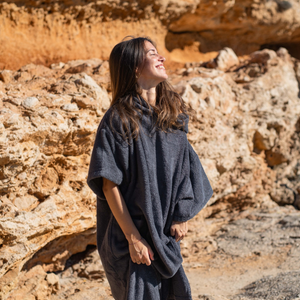 Femme a la plage portant un poncho en coton biologique coloris graphite - Atelier Dune