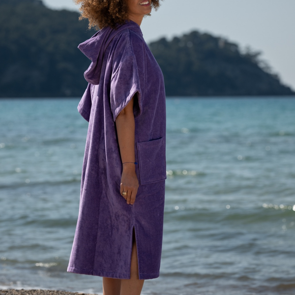 Femme au bord de la mer portant un poncho moelleux en coton biologique velours lavande - Atelier Dune