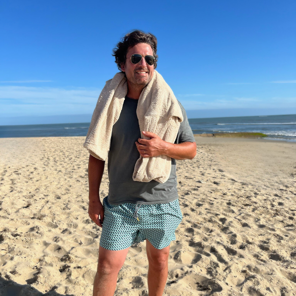 Homme au bord de la mer portant un poncho de bain coton bio sable - Atelier Dune