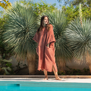 Femme au bord de la piscine portant un poncho en  coton bio terracotta - Atelier Dune