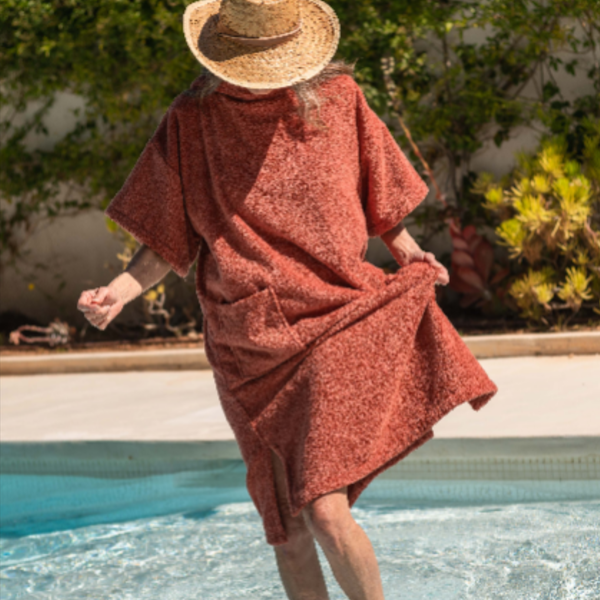 Femme au bord de la piscine portant un poncho de bain coton bio terracotta - Atelier Dune