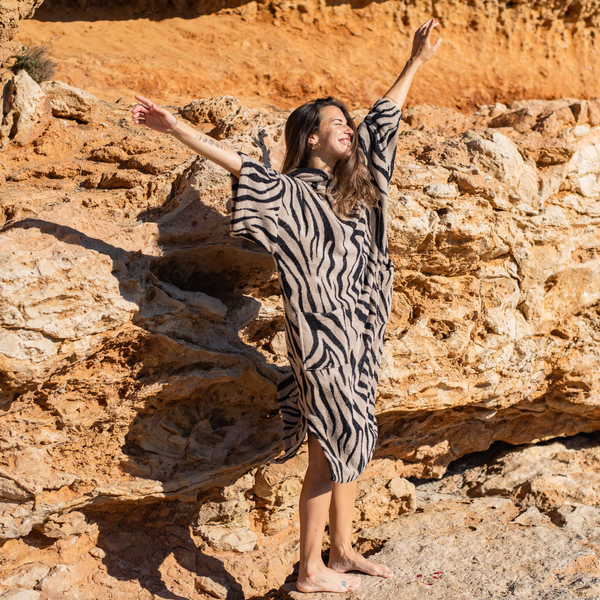 Femme souriante sur la plage en poncho de bain zèbre - Atelier Dune