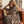 une jeune fille reve, assise dans un canapé en cuir vintage, et enveloppée dans son poncho premium en coton bio Atelier Dune, motif zebre