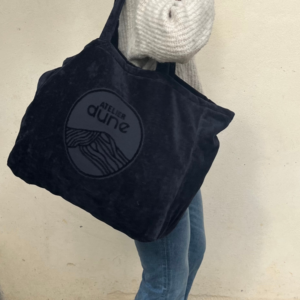 Sac cabas XL velours noir porté par une femme en pull beige