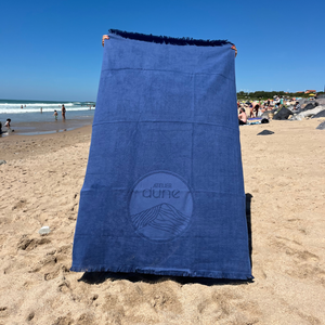Serviette de plage en coton biologique coloris outremer sur la plage - Atelier Dune