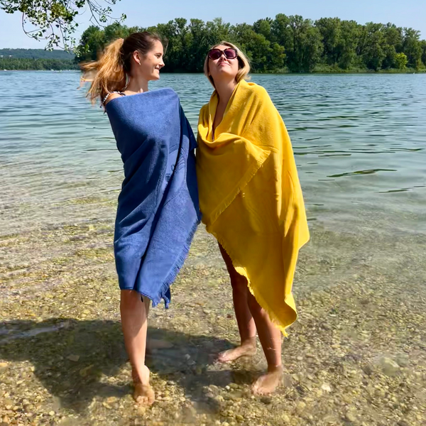 Duo de femmes dans des serviettes de plage double-face en coton biologique outremer et curry - Atelier Dune