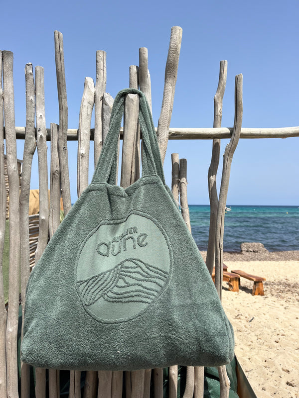 Maxi totebag en coton bio labels Gots et OekoTex avec gros logo en jaquard, grande contenance, coloris sauge, suspendu sur bois flotté à la plage - atelier dune